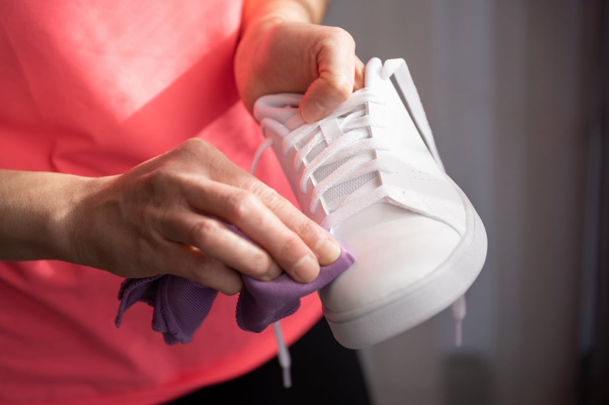 A white sneaker being wiped with a cloth during a custom session