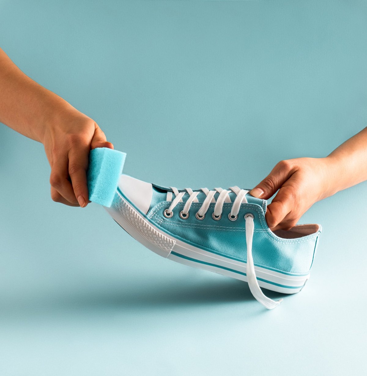 Hands wringing a sponge over a sneaker during a cleaning session