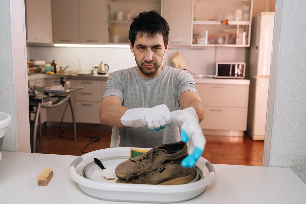 Hands pulling on protective gloves before washing a pair of sneakers