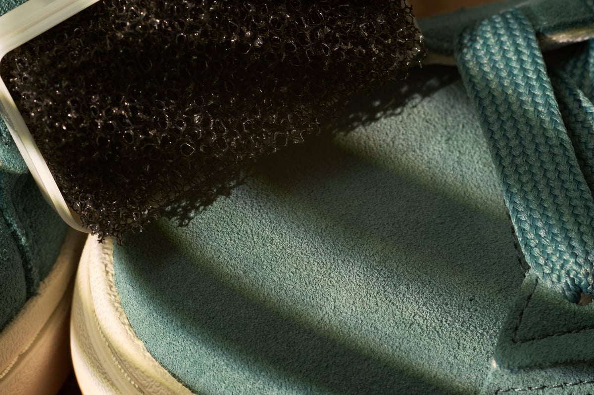 Bristle brush working lather across a fabric sneaker upper